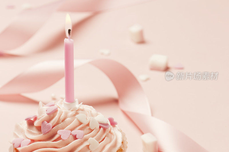 粉红色的冰杯蛋糕，点缀着心形、丝带和蜡烛