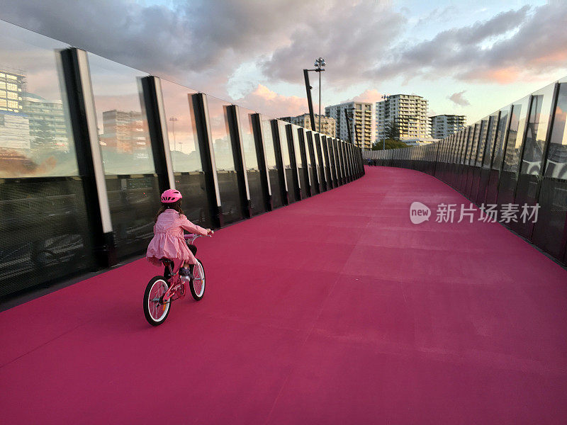 年轻的女孩骑在明亮的粉红色自行车道新西兰奥克兰