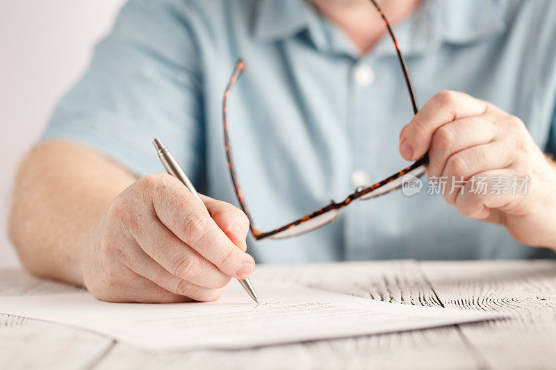特写商人的手写在一张纸上，拿着一副眼镜