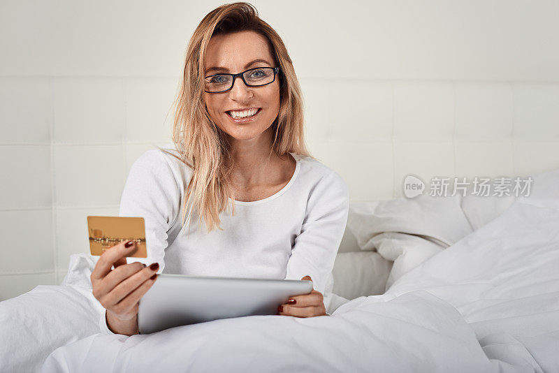 迷人的女人放松在床上网上购物