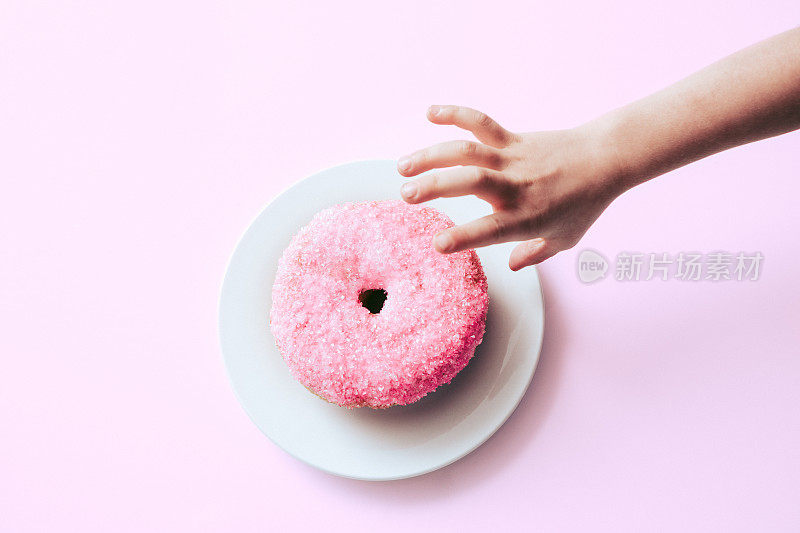手伸向新鲜的粉色甜甜圈