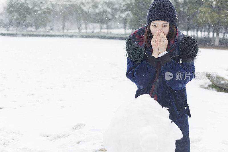 一个女人在堆完雪人后暖手