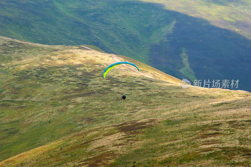 在一个阳光明媚的夏日，滑翔伞飞过山谷。