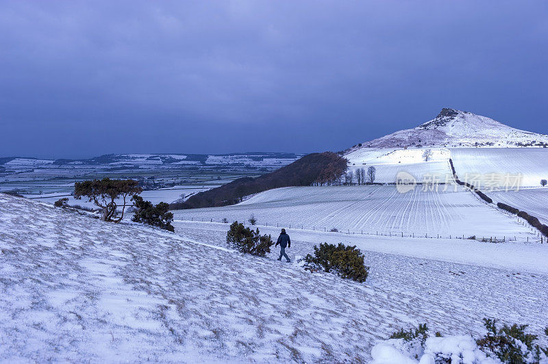 山顶边有一层雪覆盖着风景和山丘步行者在前景和在远处