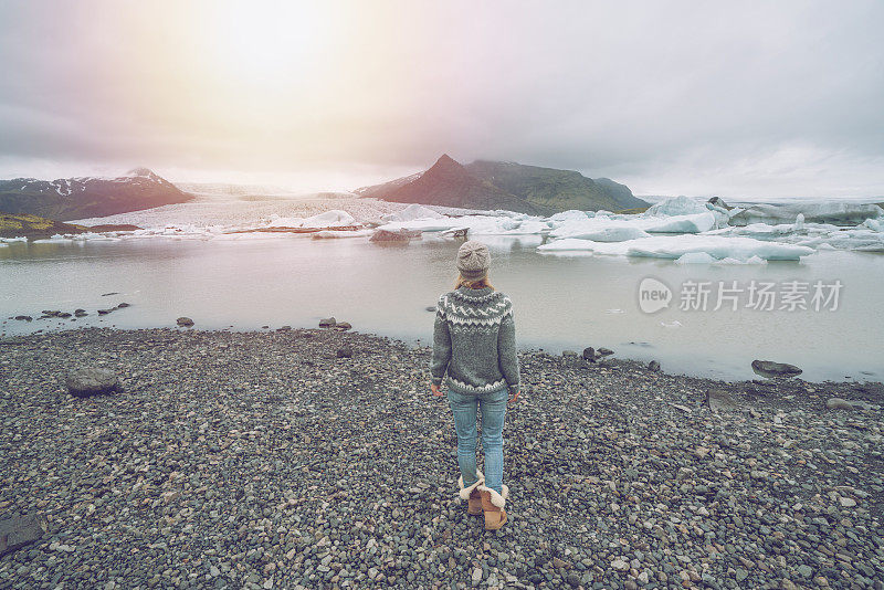 年轻女子凝视着漂浮着冰山的冰川湖。人们旅游探索和气候变化的概念