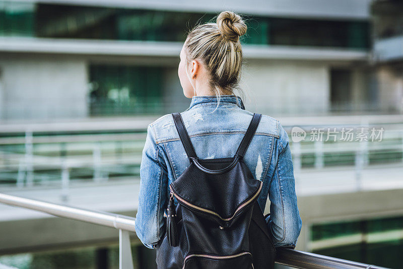 年轻女子背着背包走在欧洲的街道上