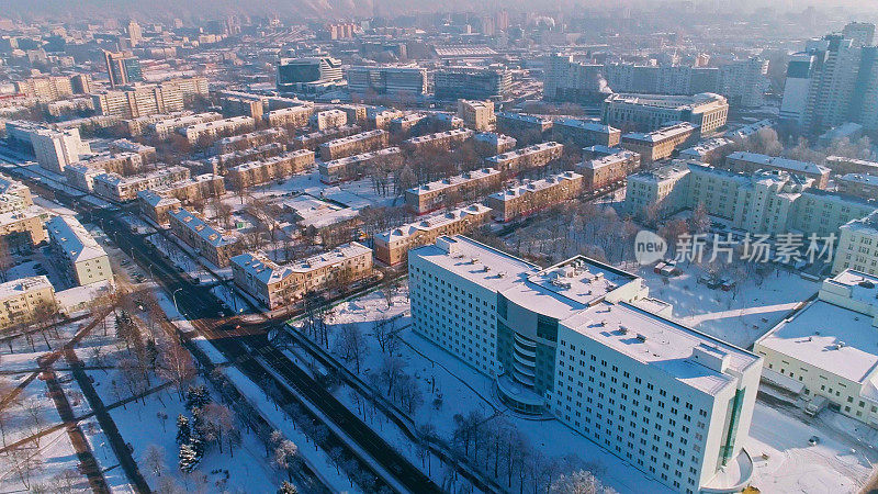 在晴朗寒冷的日子里，鸟瞰被雪覆盖的冬季城市全景。轨道摄影机运动。