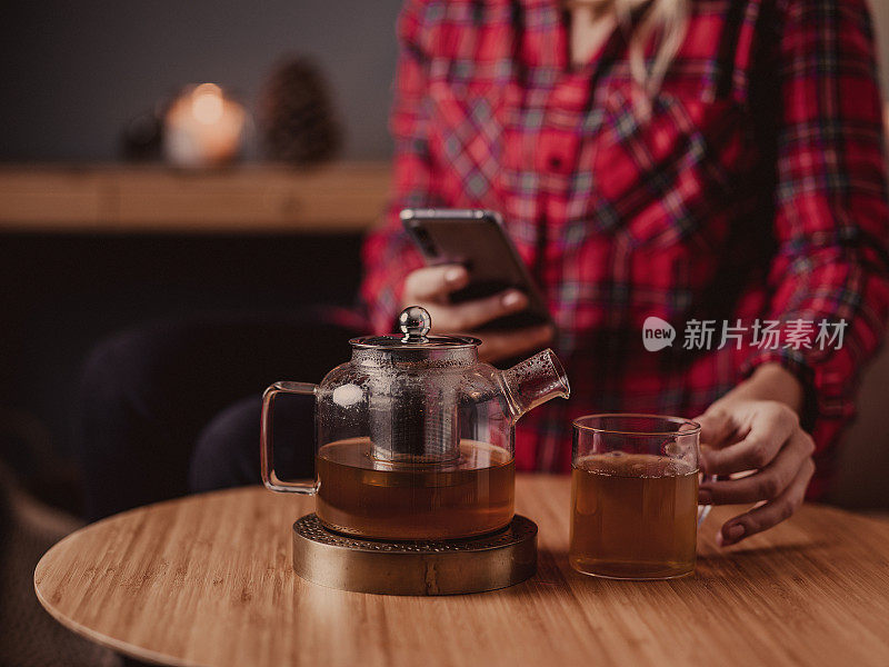 在家里用玻璃茶壶喝茶的女人