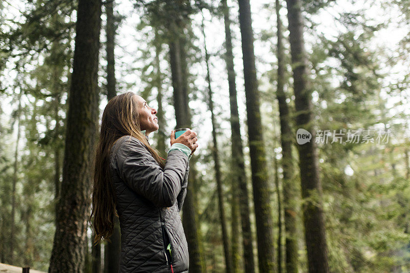 女人喝着咖啡欣赏大自然的美景