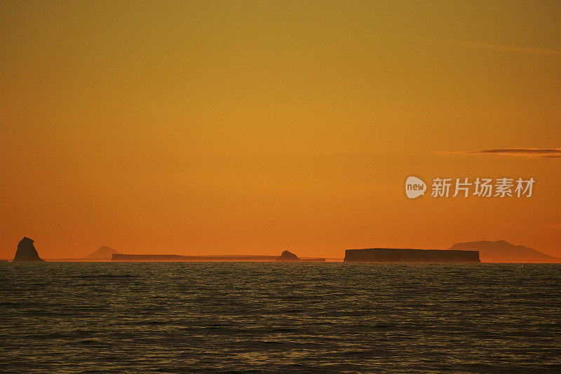 南极泻湖上的日落与漂流的冰山和雪峰的背景，勒梅尔海峡，南极洲