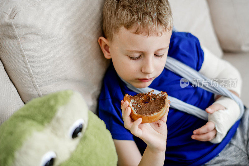 手臂骨折的孩子正在吃甜甜圈