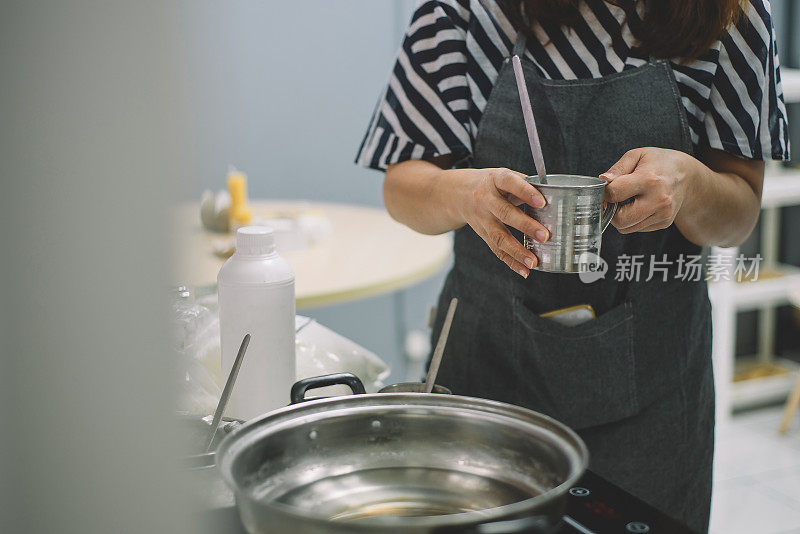 一位亚洲华人女性拿着一杯水，准备加热