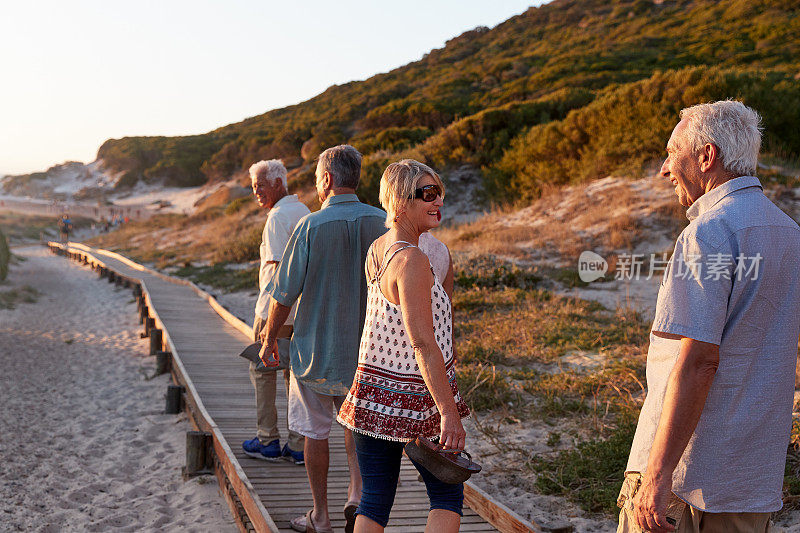 一群老年朋友在海滩上的木板路上散步