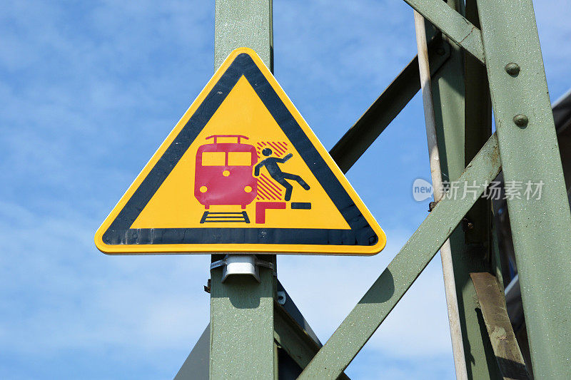德国火车站的黄色三角形警告牌上写着“禁止踏过红线”，上面有一名男子在进站前从站台上摔下来