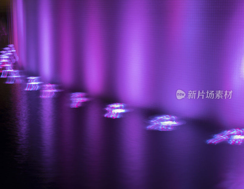 离焦的紫色灯光与反射和水流动