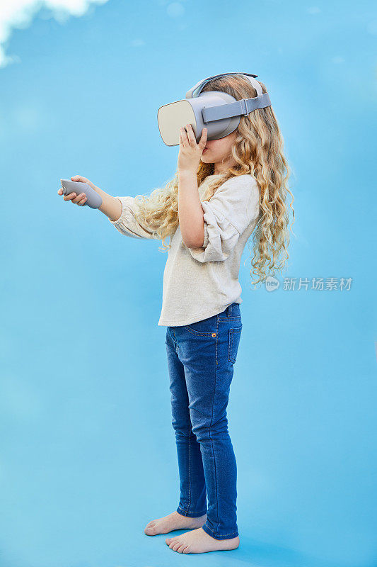 小女孩在蓝天背景下玩VR头盔