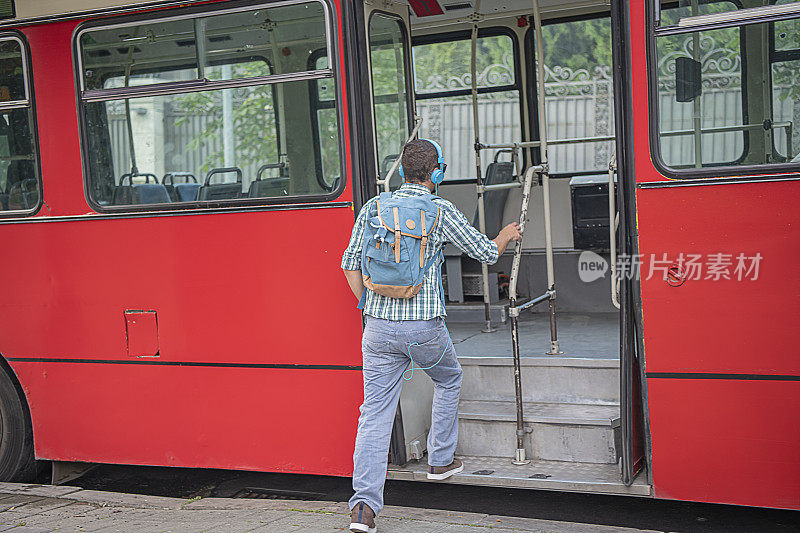 戴着耳机的年轻人正在上公交车