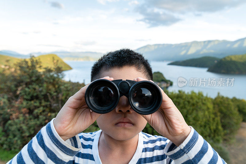 亚洲男孩用双筒望远镜看风景