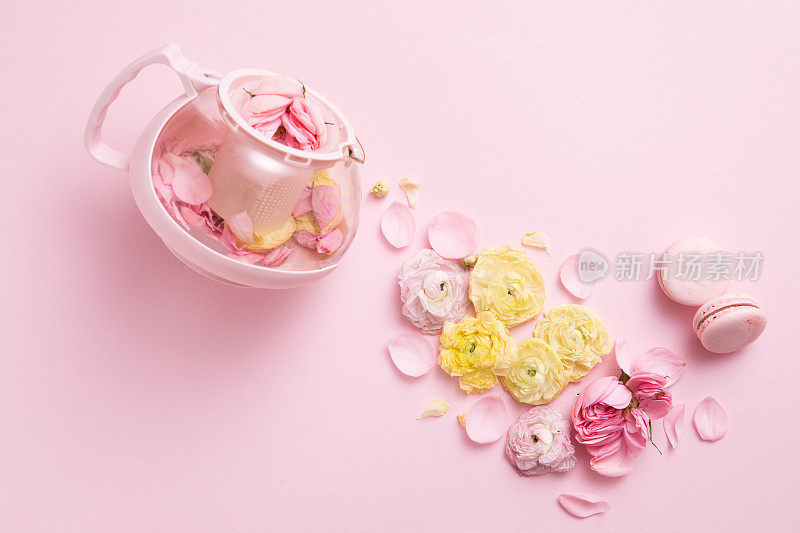 粉红色茶壶和茶杯创意布局的俯视图，粉红色背景上有花朵。