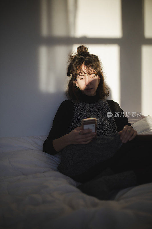 一个年轻女人看着她的手机的肖像