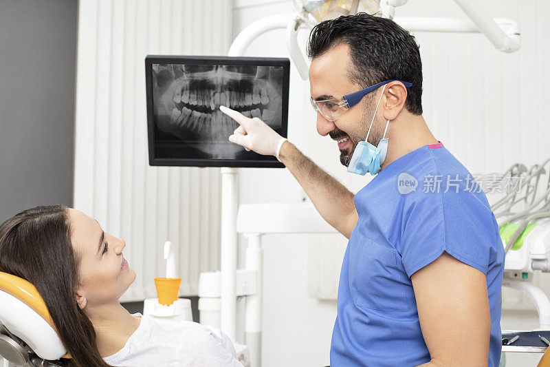 微笑的男牙医与女士谈论矫形图的结果