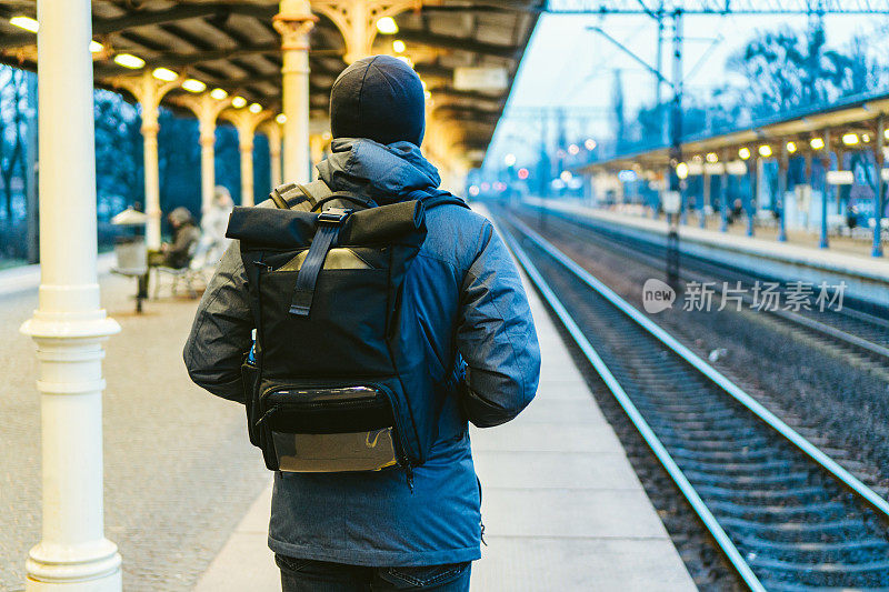 位于欧洲波兰索波特的火车站。帅哥在火车站等车。想着旅行，背着背包。旅游摄影。旅客背包站在火车站站台上