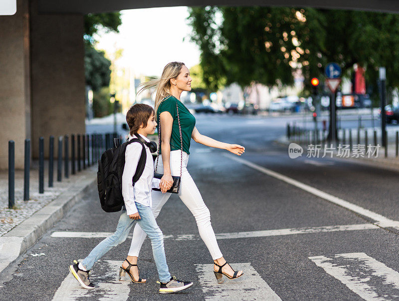 一个背着背包的小学生和妈妈正在过马路