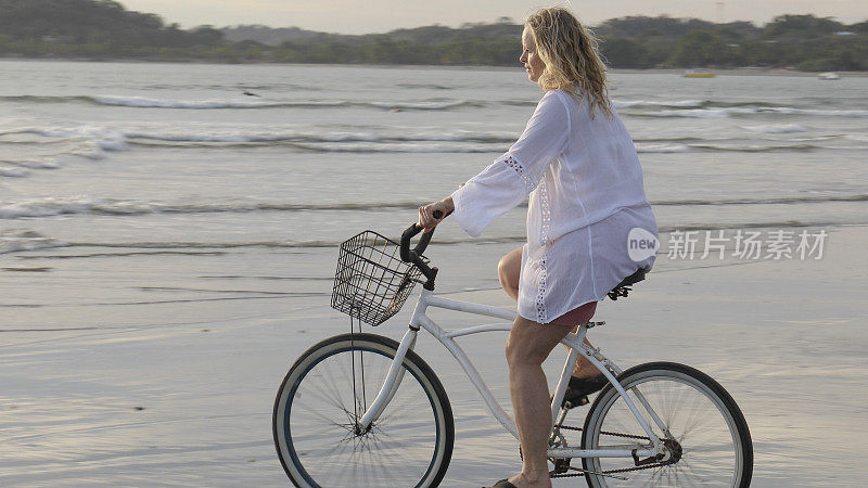 日出时分，女人沿着热带海滩骑自行车