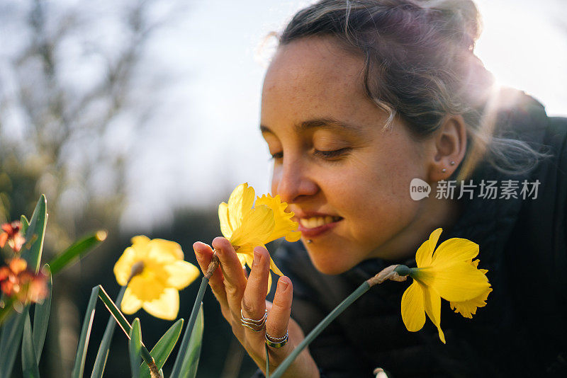 年轻女子俯身闻花香