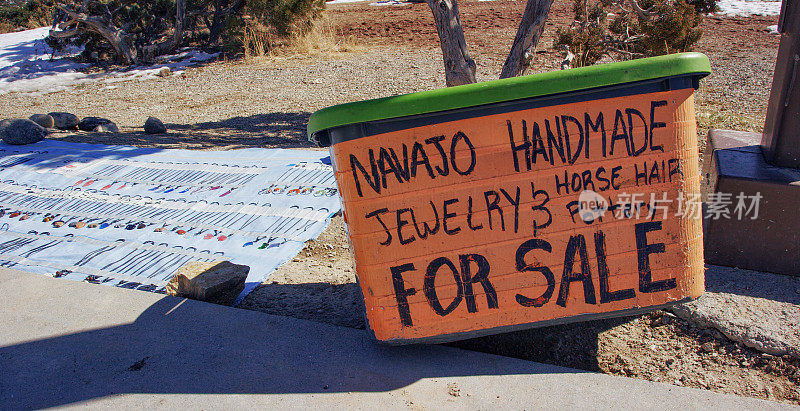 一个牌子上写着“出售纳瓦霍手工珠宝和马鬃陶器”，旁边是美国本土风格的珠宝