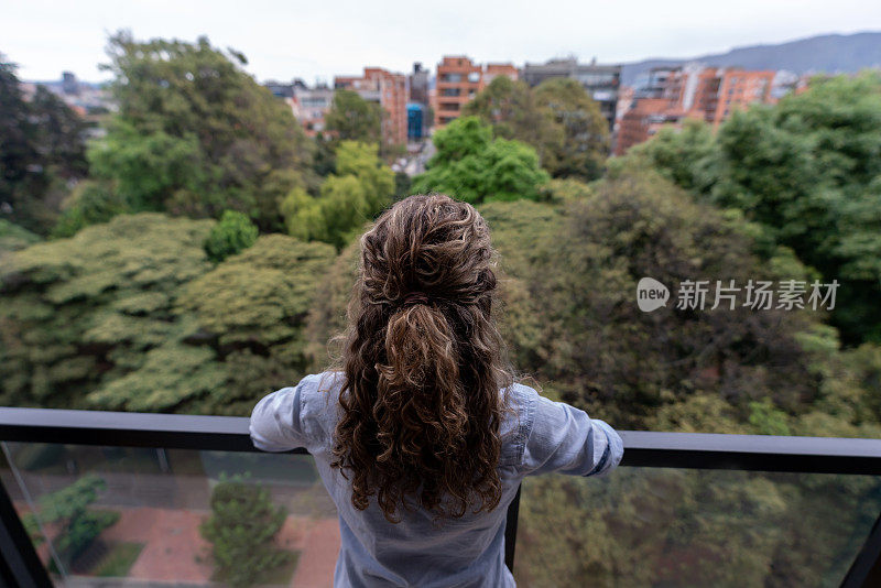 被隔离的妇女望着阳台上的景色，渴望出去