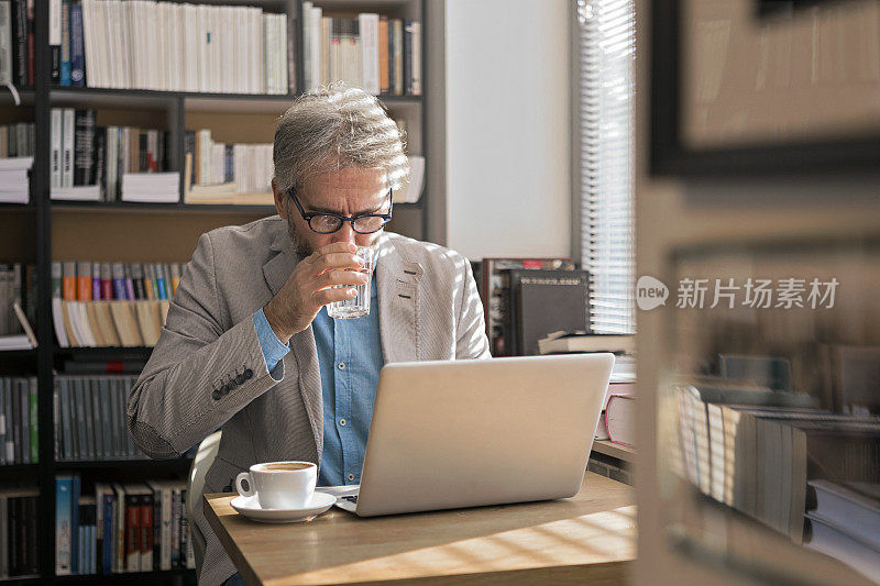 一个成年人拿着笔记本电脑在书店喝咖啡