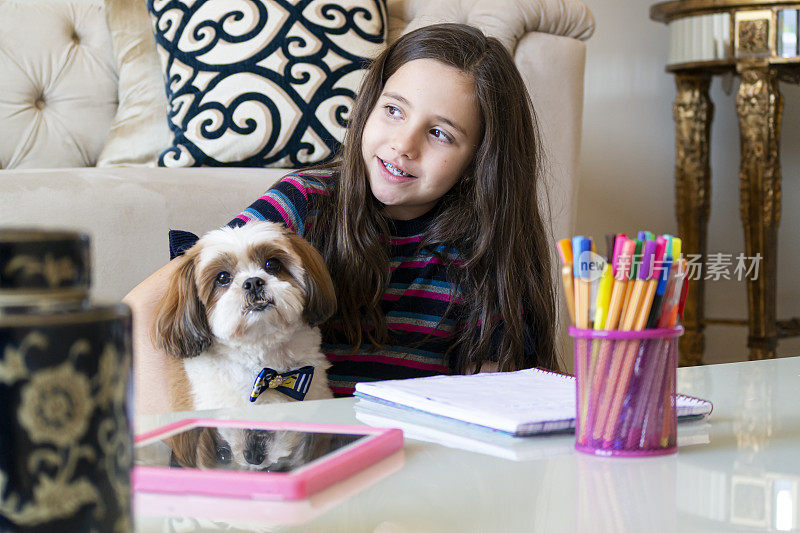 小女孩和她的狗在家里学习。