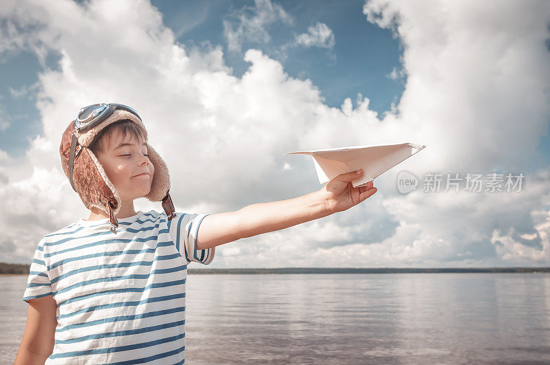 男孩戴着飞行员帽玩纸飞机