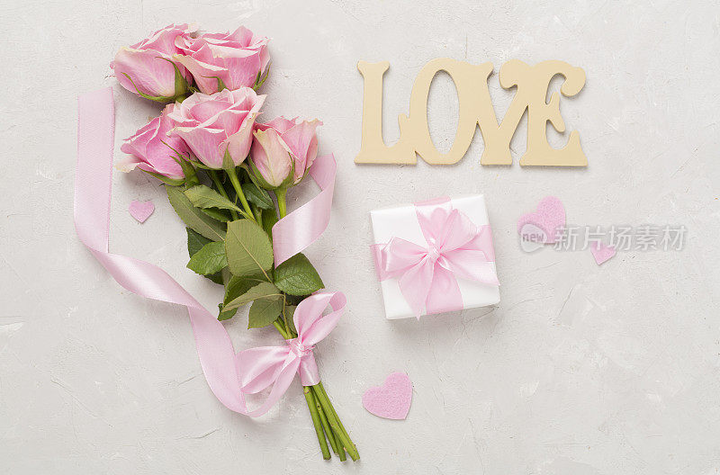 粉红色玫瑰与心和礼盒在混凝土背景，俯视图。情人节概念