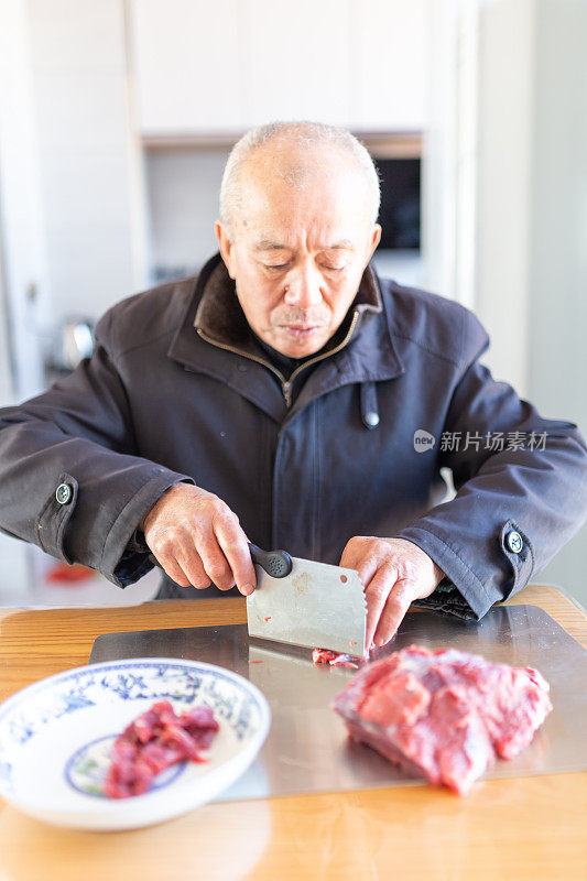 一位老人在餐厅切牛肉