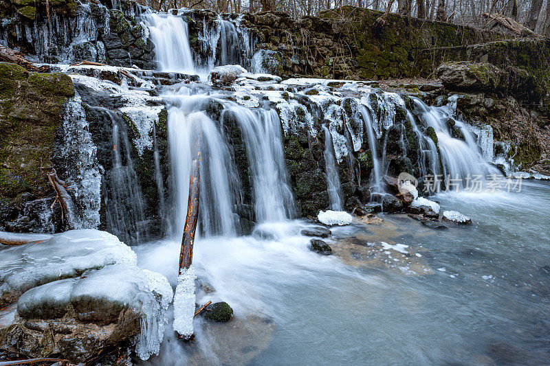 冰柱悬挂在瀑布的一侧，创造了令人惊叹的冬季景色。瀑布位于山区，岩石被冰覆盖。
