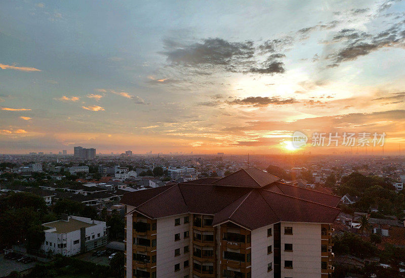 在雅加达市中心欣赏黎明的日出，黄色的阳光和清澈的蓝天，以及公寓大楼的天际线，背景是晨雾和摩天大楼。