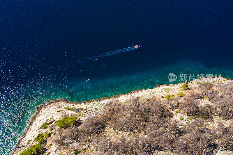 一艘载着游客的小船缓缓地漂在清澈的水面上。神奇的海岸线。航空摄影。山上绿树成荫，大海湛蓝透明。Makarska里维埃拉。克罗地亚