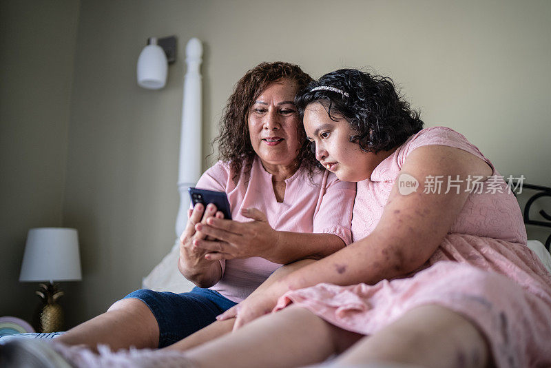 母亲和精神运动障碍的女儿在家使用手机