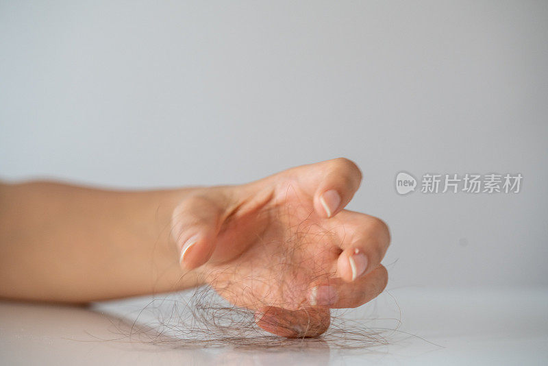 女人在浴室背景上的梳子上失去头发