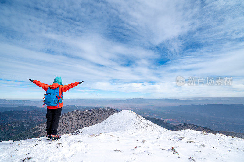 图为，登山女领队在山顶观看森林和山脉的美景，张开双臂庆祝胜利