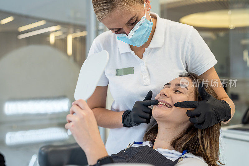 一位年轻的女牙医正在牙科诊所为一位女病人做牙科检查。