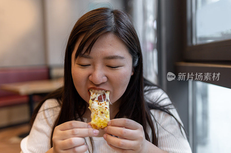 漂亮的年轻女子在咖啡馆吃披萨。