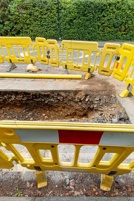 英国的道路工程正在挖掘当地的柏油路面，以修复地下的公用管道，并设置安全屏障和标志