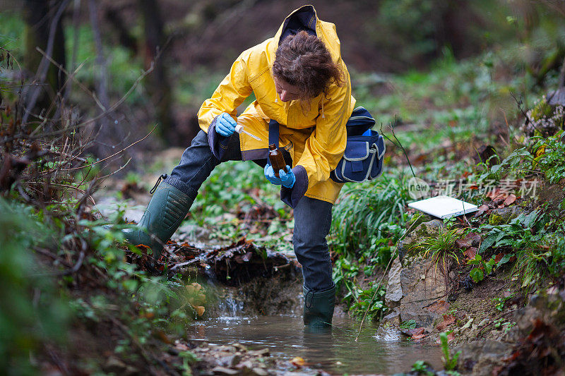 中年生物学家在农村的一条溪流中采集水样作进一步检查