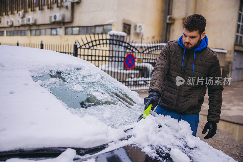 年轻人正在清除汽车上的积雪