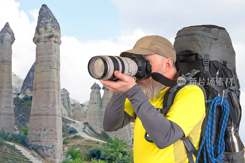 旅游摄影师背着背包，在山上拍摄大自然之美。大自然在山间漫步