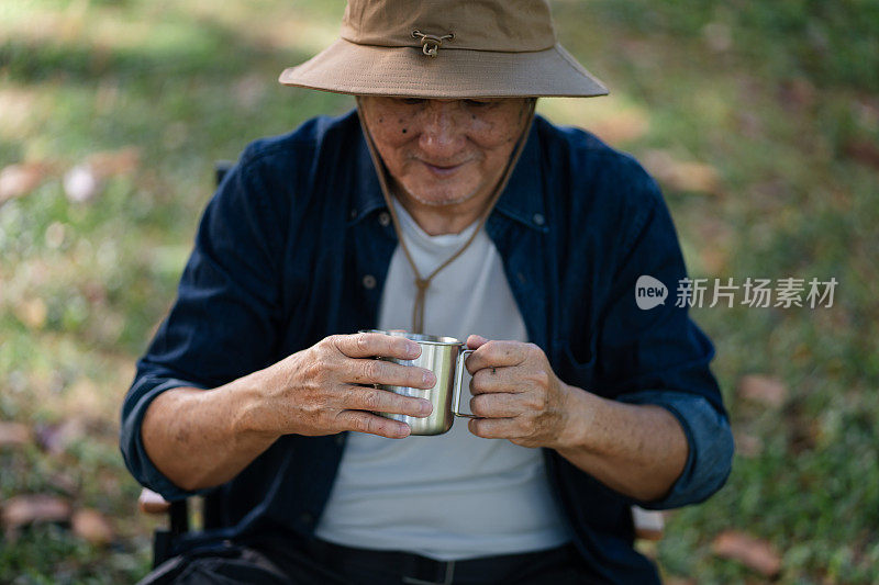 资深亚洲男子手持装满咖啡的不锈钢杯的特写