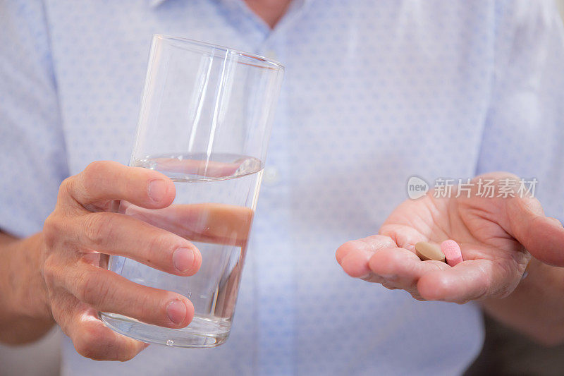 特写手病人老人服药和饮水，医疗和保险，保健和药品，老人生病和服用阿司匹林。